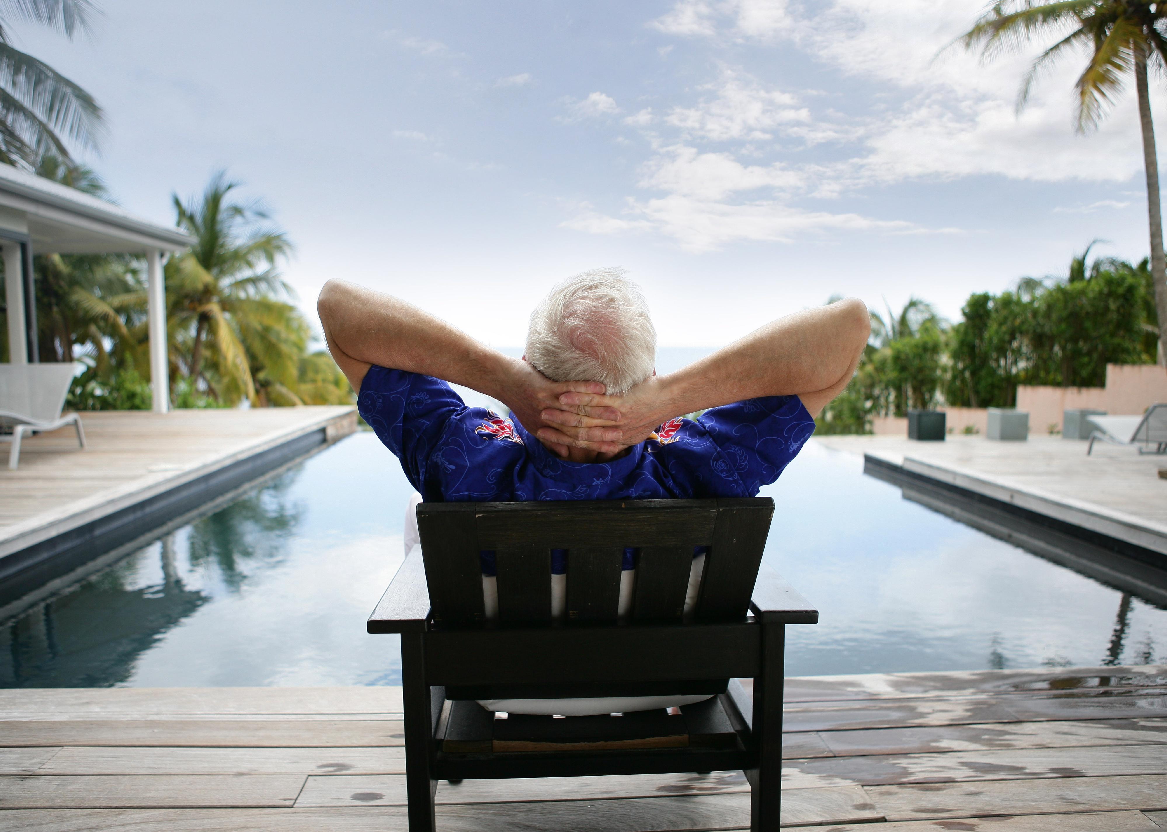 Senior man relaxing outside by swimming pool.
