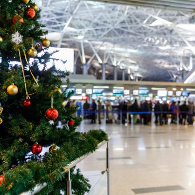 Christmas tree in an airport and people at the check-in counters in the background.