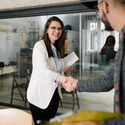 Young woman greeting a recruiter with a handshake.