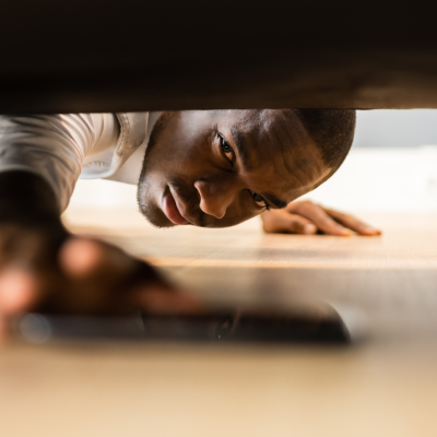 A man pulling a phone out from under a couch.