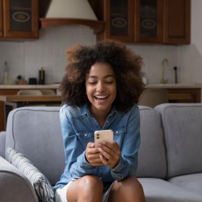 A girl laughing while looking at a phone.