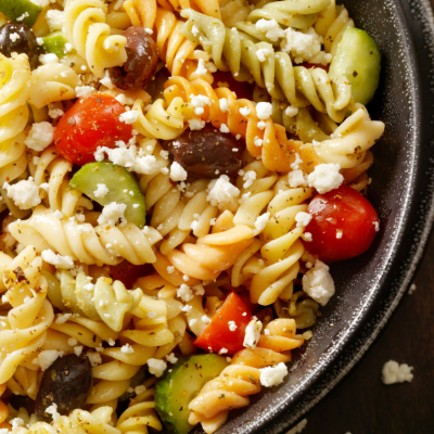 Greek pasta salad with tomato, black olives, cucumber, and feta cheese.