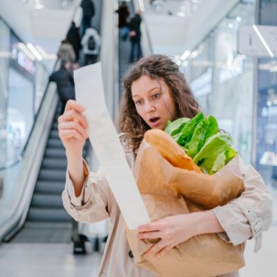 A woman looking surprised at a grocery receipt.