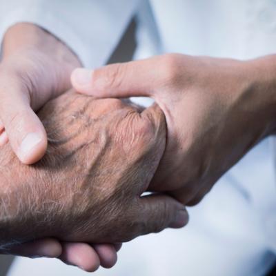 A medical professional holding an elderly pair of hands.