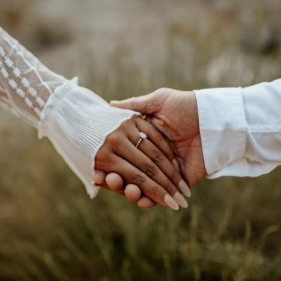 Two people holding hands in wedding attire.