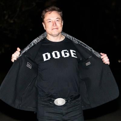Elon Musk reveals a DOGE t-shirt and a Tesla belt buckle before entering the White House on March 9, 2025.