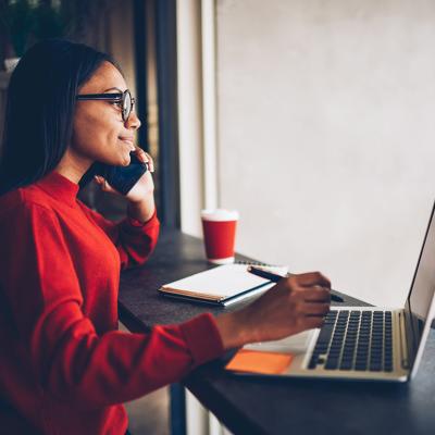 A professional copywriter taking a phone call while working with a laptop in a cafe.