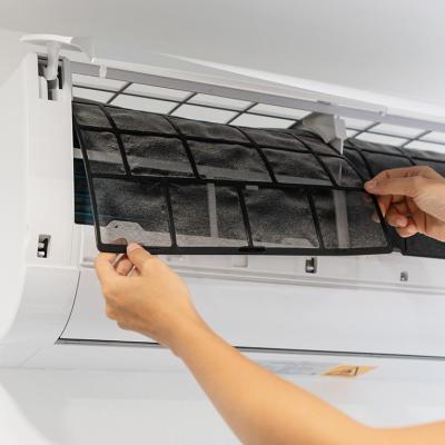 Person pulling out a dirty air conditioner filter from a mini-split unit.
