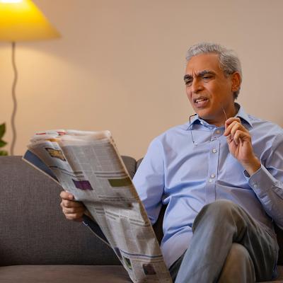 Senior man reading a newspaper in confusion.