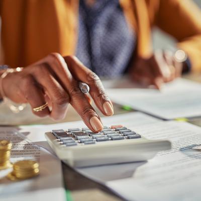 Tax professional using a calculator while reviewing finance documents.