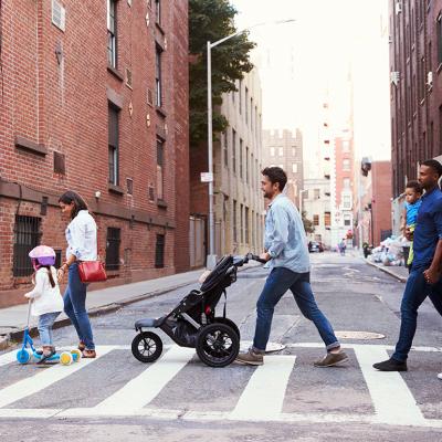Two families crossing a road along an apartment neighborhood.