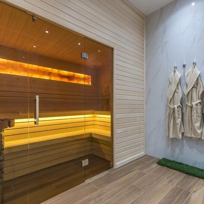 A modern home sauna with bathrobes hanging on its wall.