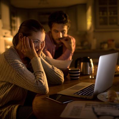Young couple stressfully looking at their laptop.