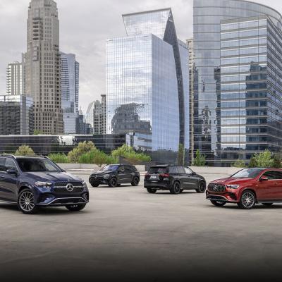 Four models in blue, black and red of the 2024 Mercedes-Benz GLE Coup parked on a rooftop with skyscrapers in the background.
