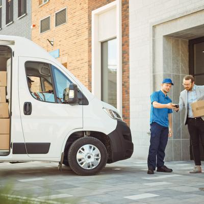 Delivery man gives postal package to its consignee in a business address.
