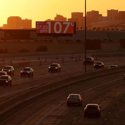 A billboard shows the current temperature over 100 degrees on June 05, 2024 in Phoenix, Arizona as drivers travel on the freeway in the foreground in the shadow of the setting sun.