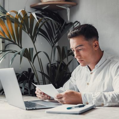 A confused young college student reading a debt letter.