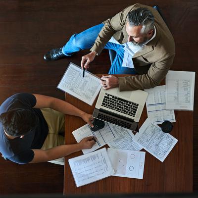 Two businessmen discussing strategy with accounting documents on their table.