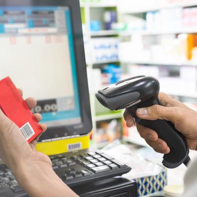 Pharmacist scanning price on a box of medicine.