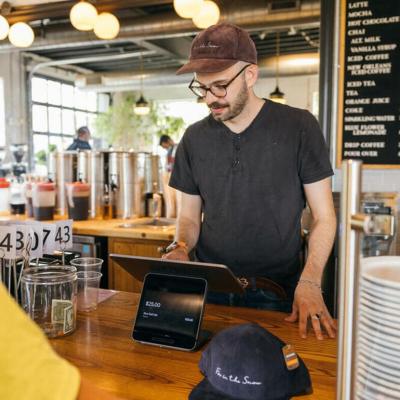 A restaurant staff mans the cashier and inputs order from a customer.