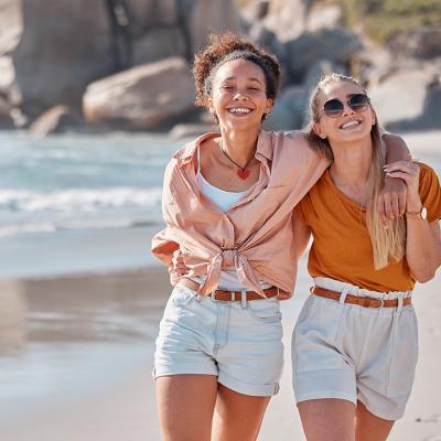 A happy lesbian couple walking on the beach.