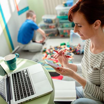 Mother working from home with a laptop and phone.