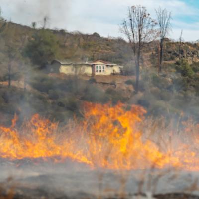 A wildfire blurs the view of a home from a distance.