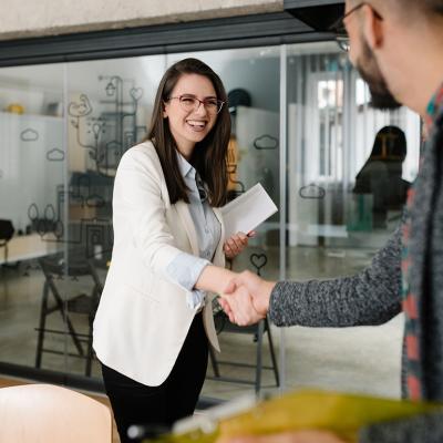 Businesswoman greeting a finance professional with a firm handshake.