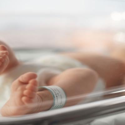 Newborn baby lying in bassinet in hospital with toes and feet in focus.