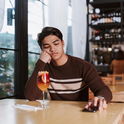 Young man who was ghosted by his date sits alone disappointed in a restaurant.
