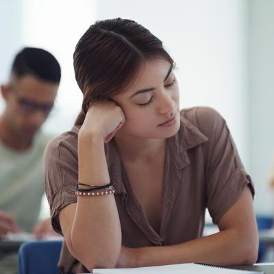 Young female college student feeling burned out in a classroom.
