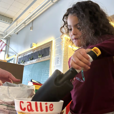 A preschooler at Palmer Elementary in Denver prepares to plant wildflowers in a pot she decorated. 