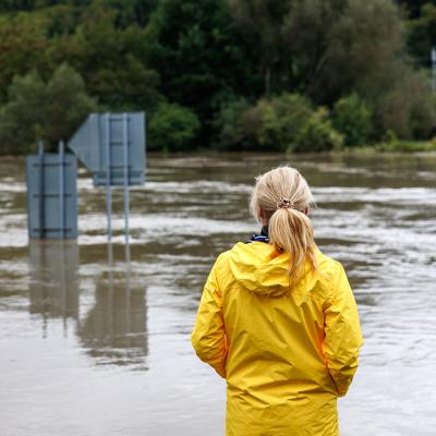 A woman in a raincoat looking over a huge flood.