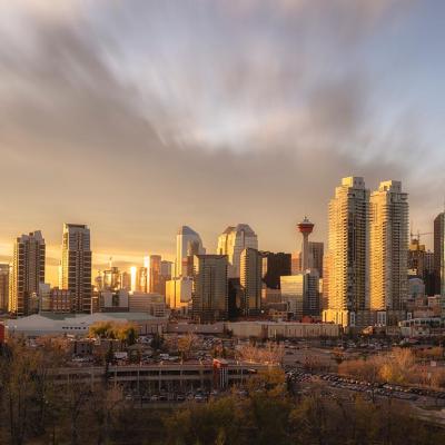 Skyline of Calgary during sunset with golden light reflecting off skyscrapers.