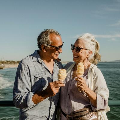 An older couple eating ice cream while standing on the Santa Monica pier.