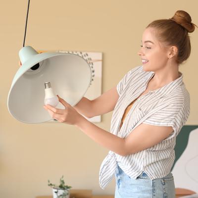 Young woman screwing light bulb into a ceiling lamp.
