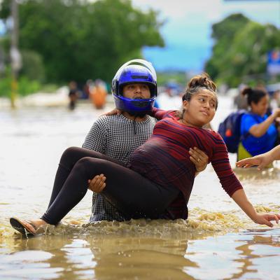 A man carries a pregnant woman through a flooded road in La Lima, Honduras after the low pressure system "Eta" caused heavy rainfall throughout the region.
