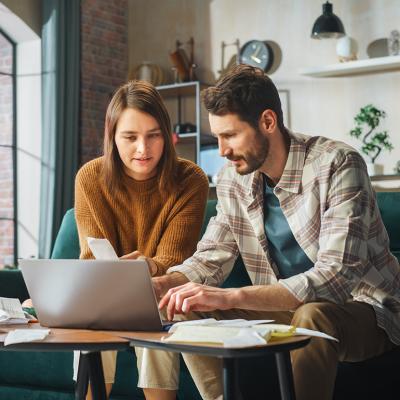 Young couple organizing bills with a laptop.