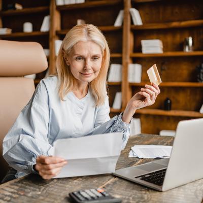 Senior businesswoman using company card to pay a bill online.