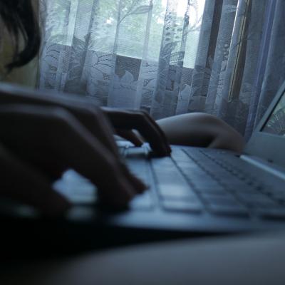 Silhouette of a person typing on a laptop at home.