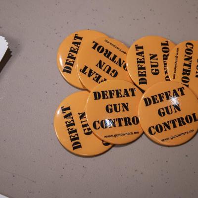 Orange "Defeat gun control" buttons set out on a table for people after they sign their name to give to legislators working on gun control bills.