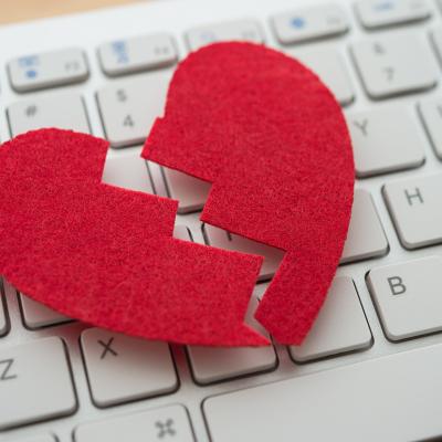 A red broken heart cutout on top of a white keyboard.