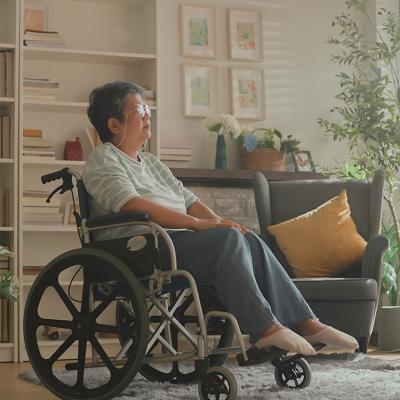 Senior woman in a wheelchair staring at a window in the living room.