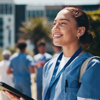 A nursing student happily using a tablet inside campus.