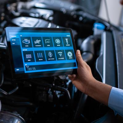 Car mechanic using a tablet to diagnose a car's components' issues.