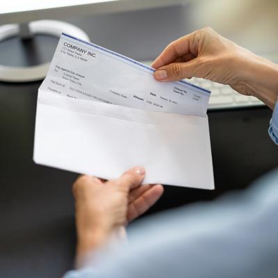 Worker pulling out a paycheck from its envelope.