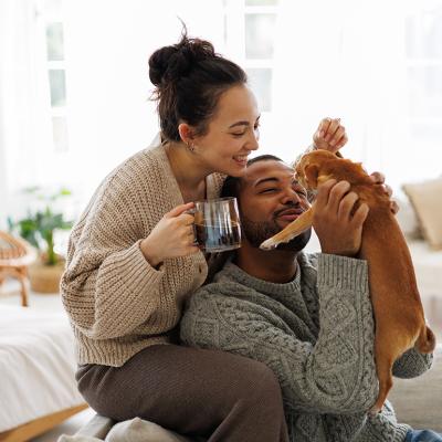 Happy couple at home playing with their dog.