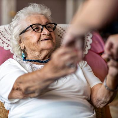 An elderly woman being assisted by her caregiver to stand up.