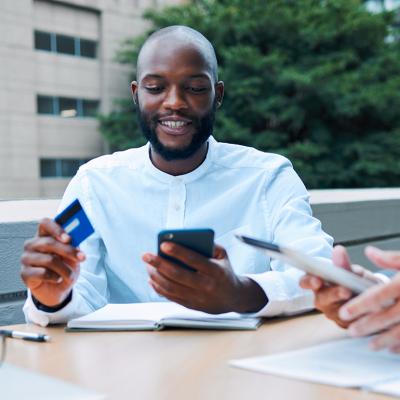 A young black businessman using a credit card to pay for a coffee shop transaction.