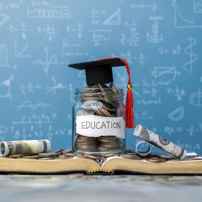 Photo illustration showing concept of college education cost with a jar of savings, a graduation cap, books and a blackboard with math in the background.
